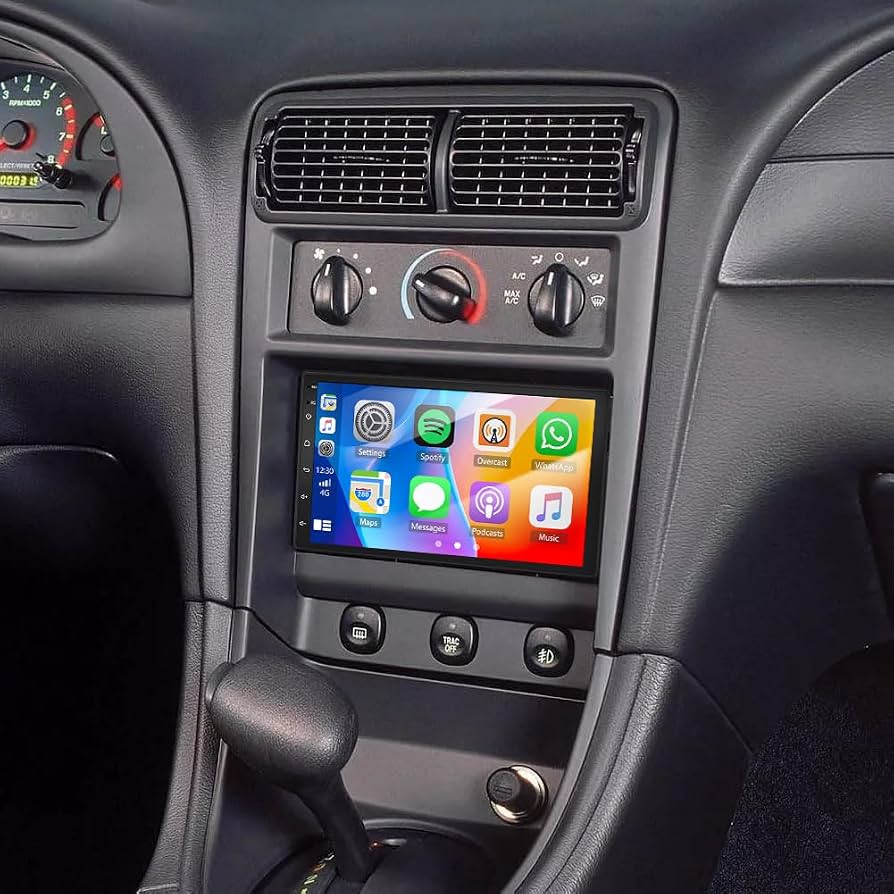 A custom car dashboard featuring an installed aftermarket touchscreen head unit with Apple CarPlay, media apps, and updated climate controls.