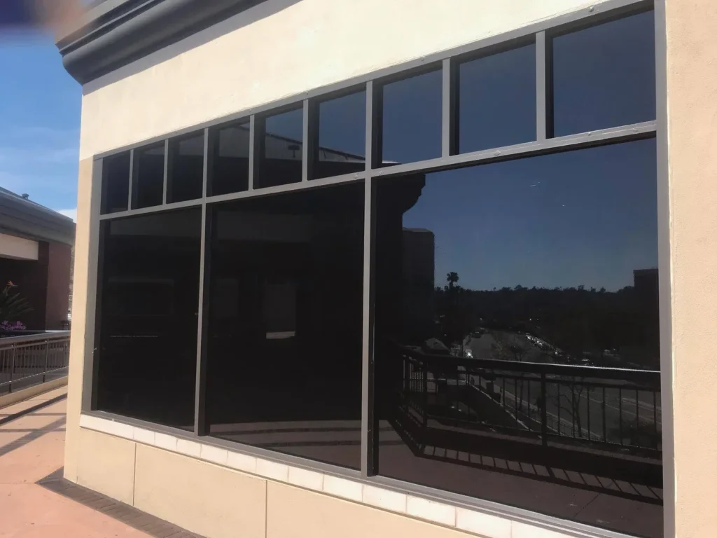 Large commercial storefront windows professionally installed with dark reflective solar tint film.